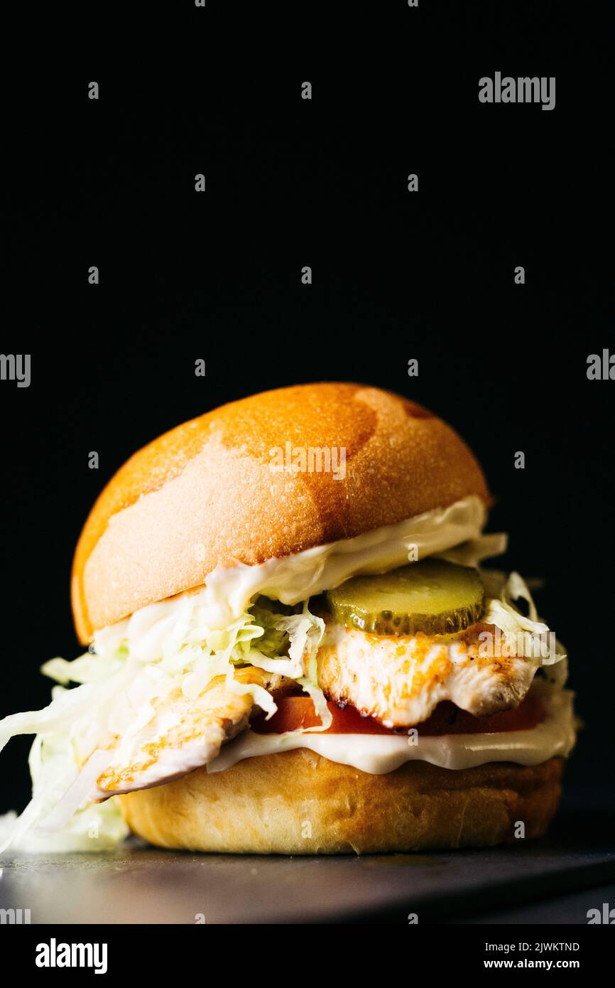 Chicken Burger mit Gemüse auf schwarzem Hintergrund Stockfoto