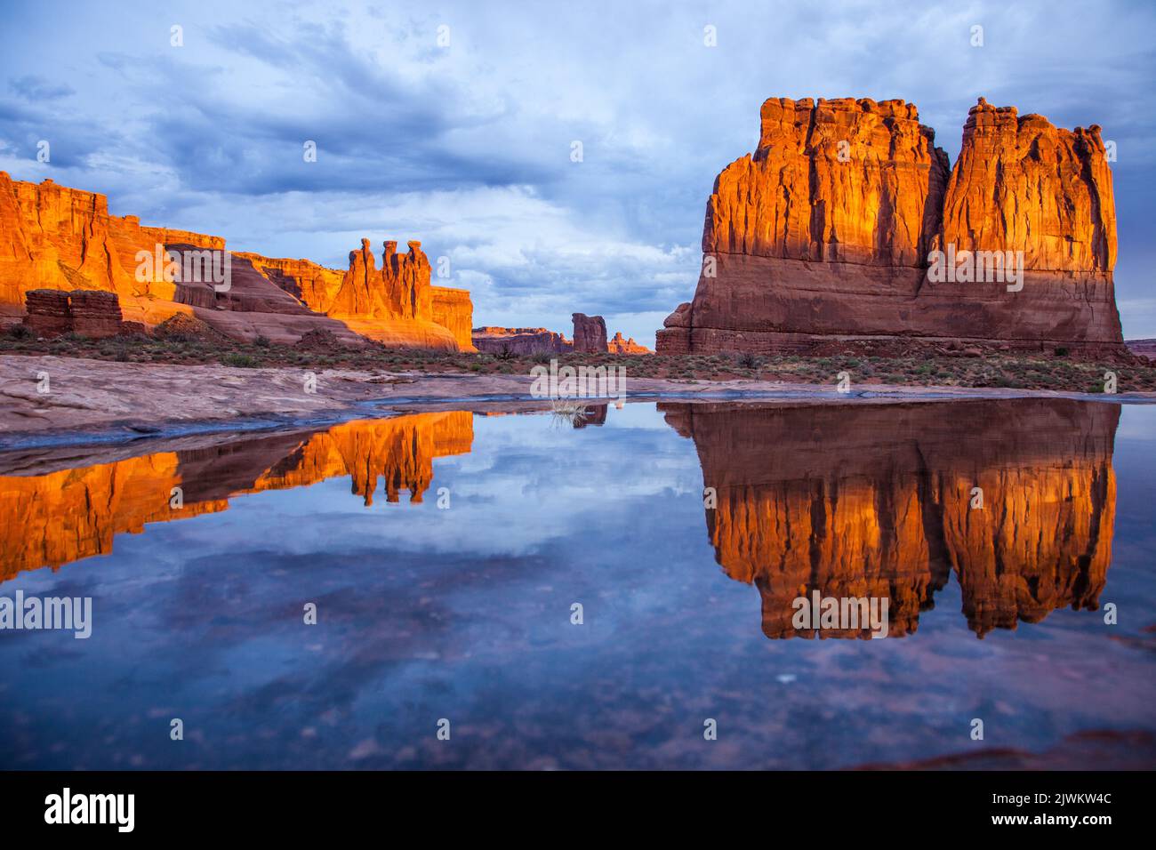 Die drei Klatsch, Sheep Rock und The Organ, spiegelten sich in einem ephemeren Regenwasserpool im Arches National Park, Moab, Utah, wider. Abschnitt „Courthouse Towers“. Stockfoto