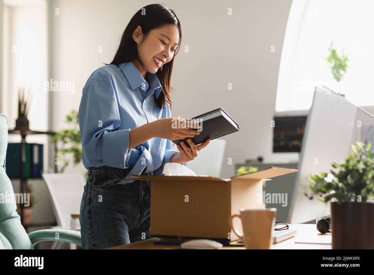 Fröhliche Asiatische Geschäftsfrau Auspacken Box Holding Buch Im Büro Stehen Stockfoto