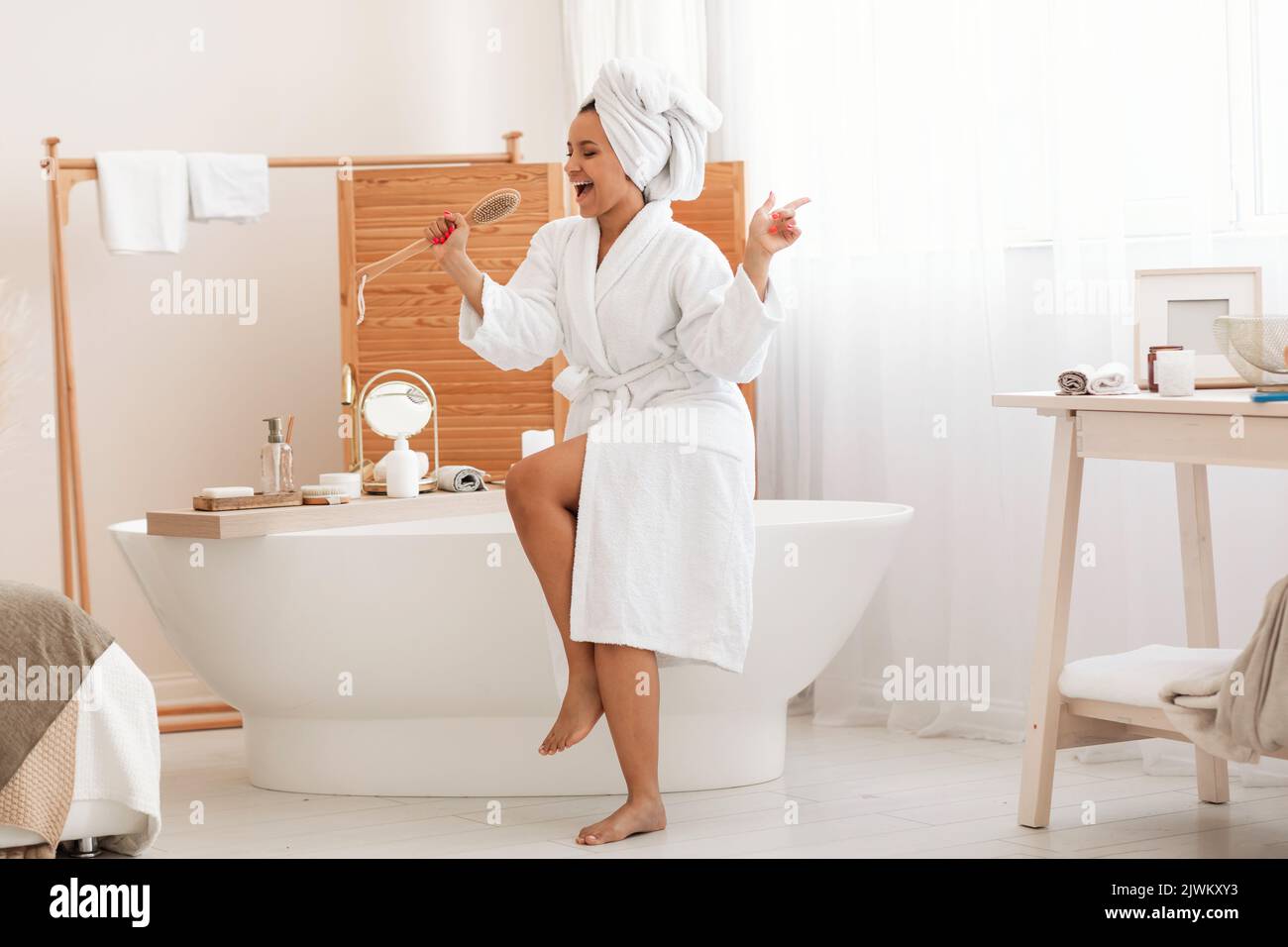 Glücklich Weiblich Singen Holding Hölzerne Bürste Mit Spaß Im Badezimmer Stockfoto