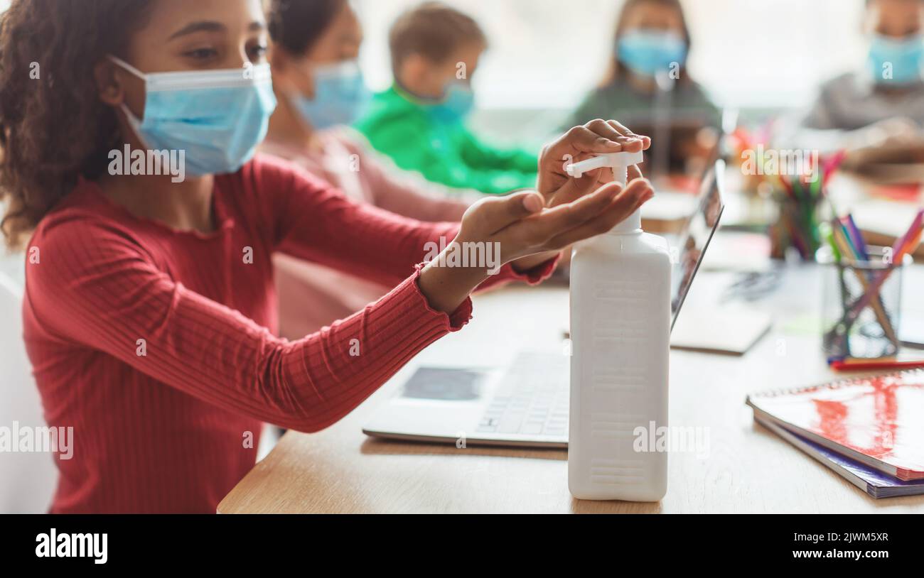 Schwarzes Schulmädchen, Das Desinfektionsmittel Anwendet, Desinfizierende Hände Im Klassenzimmer In Der Schule Stockfoto
