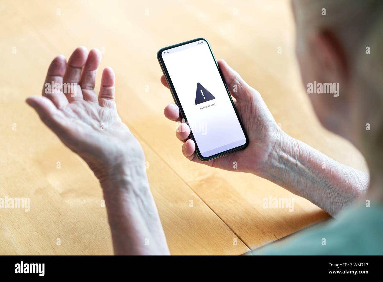 Leitender Mitarbeiter, der Probleme mit Telefon und Technologie hat. Alte Frau mit Fehlermeldung auf dem Smartphone-Bildschirm. Frustrierte Dame mit technischen Problemen. Stockfoto