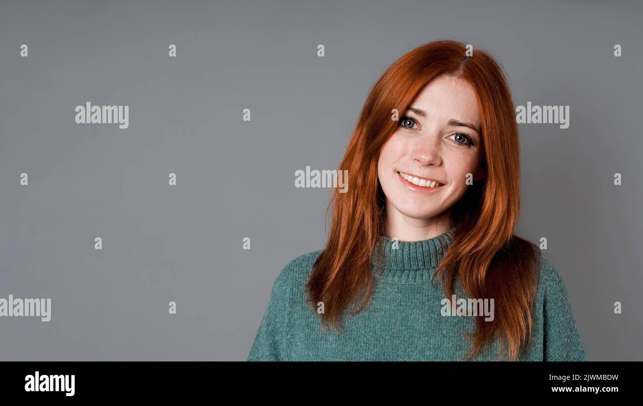 Glückliche Frau mit mittlerem Erwachsenen und einem großen, toothy Lächeln und langen roten Haaren Stockfoto