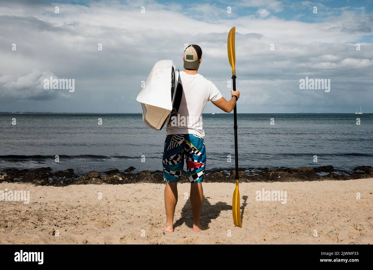 Der Mann stand und schaute auf das Meer und hielt ein Kajak bereit, um es zu erkunden Stockfoto