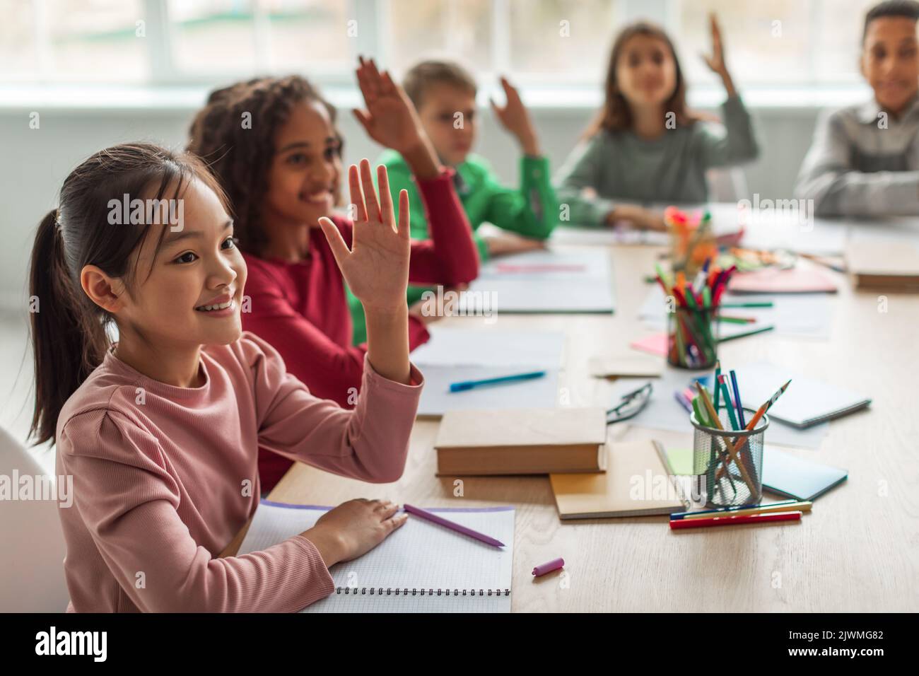 Multiethnische Schulkinder Lernen, Während Des Unterrichts Die Waffen Zu Heben Stockfoto