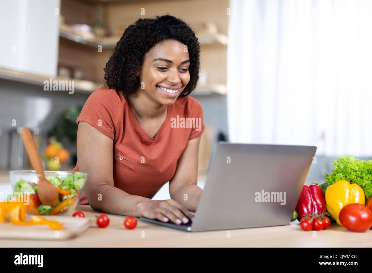 Froh junge afroamerikanische Bloggerin, die auf dem Laptop tippt, haben Online-Chat Stockfoto