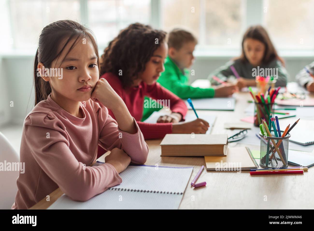 Unglücklich Asiatisch Schulmädchen Denken Sitzen Mit Verschiedenen Klassenkameraden Im Klassenzimmer Stockfoto