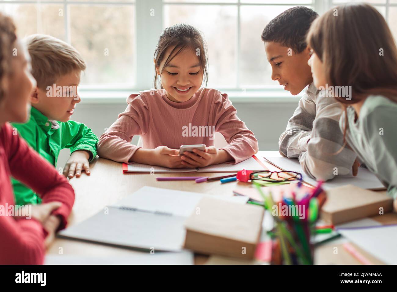 Diverse Schulkinder, Die Während Der Pause Im Klassenzimmer Das Mobiltelefon Benutzen Stockfoto