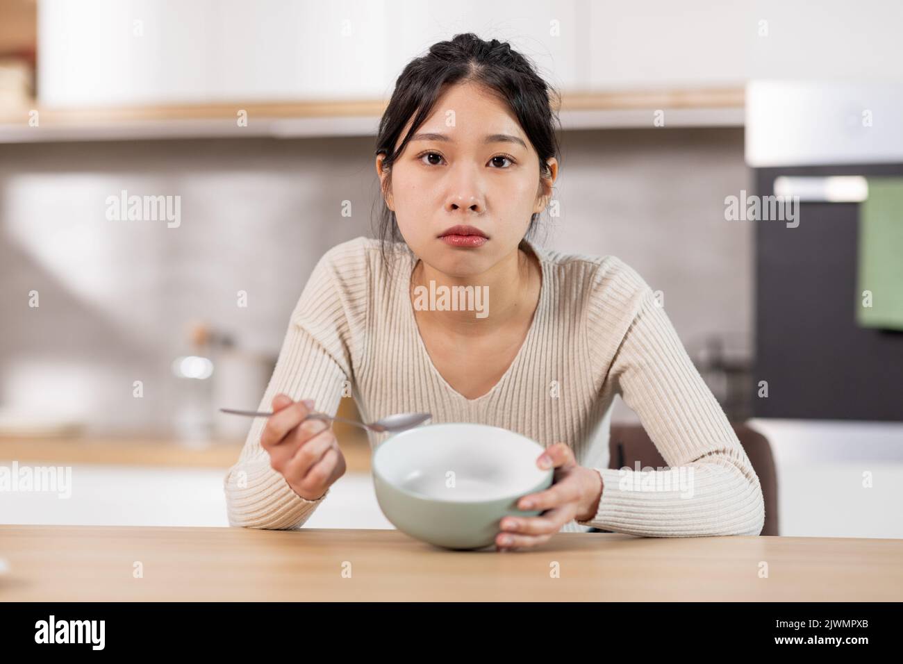 Unglückliche chinesische Frau zeigt ihren leeren Teller Stockfoto