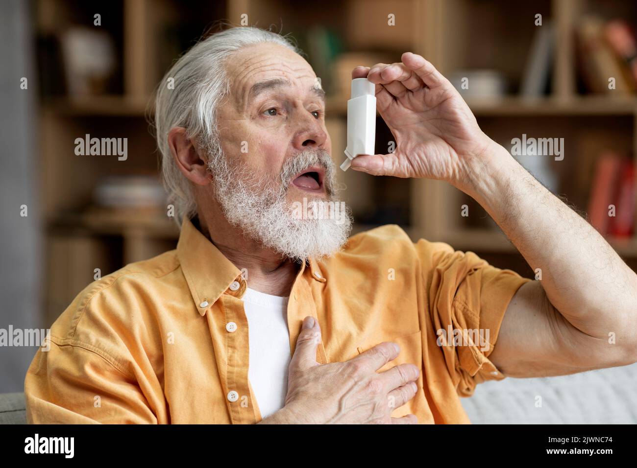Älterer Mann, der Asthma-Inhalator für Allergien verwendet Stockfoto