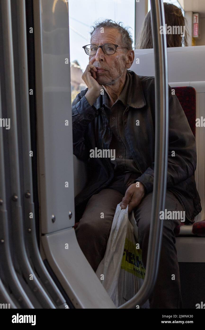 Mann in Gedanken auf Straßenbahn hält seine Lebensmittel Stockfoto