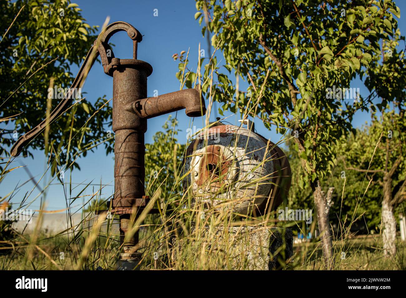 Traditionelle alte rostige Wasserpumpe, antiker Wasserbrunnen im Hinterhof Stockfoto