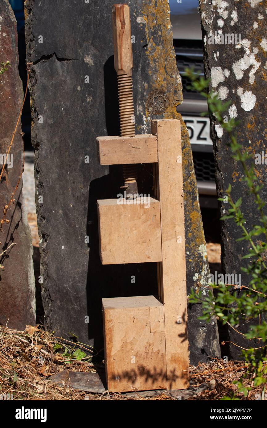 Auf dem braunen Gras sitzt ein sehr großer, tragbarer Holzschreinerschraubstock. Stockfoto