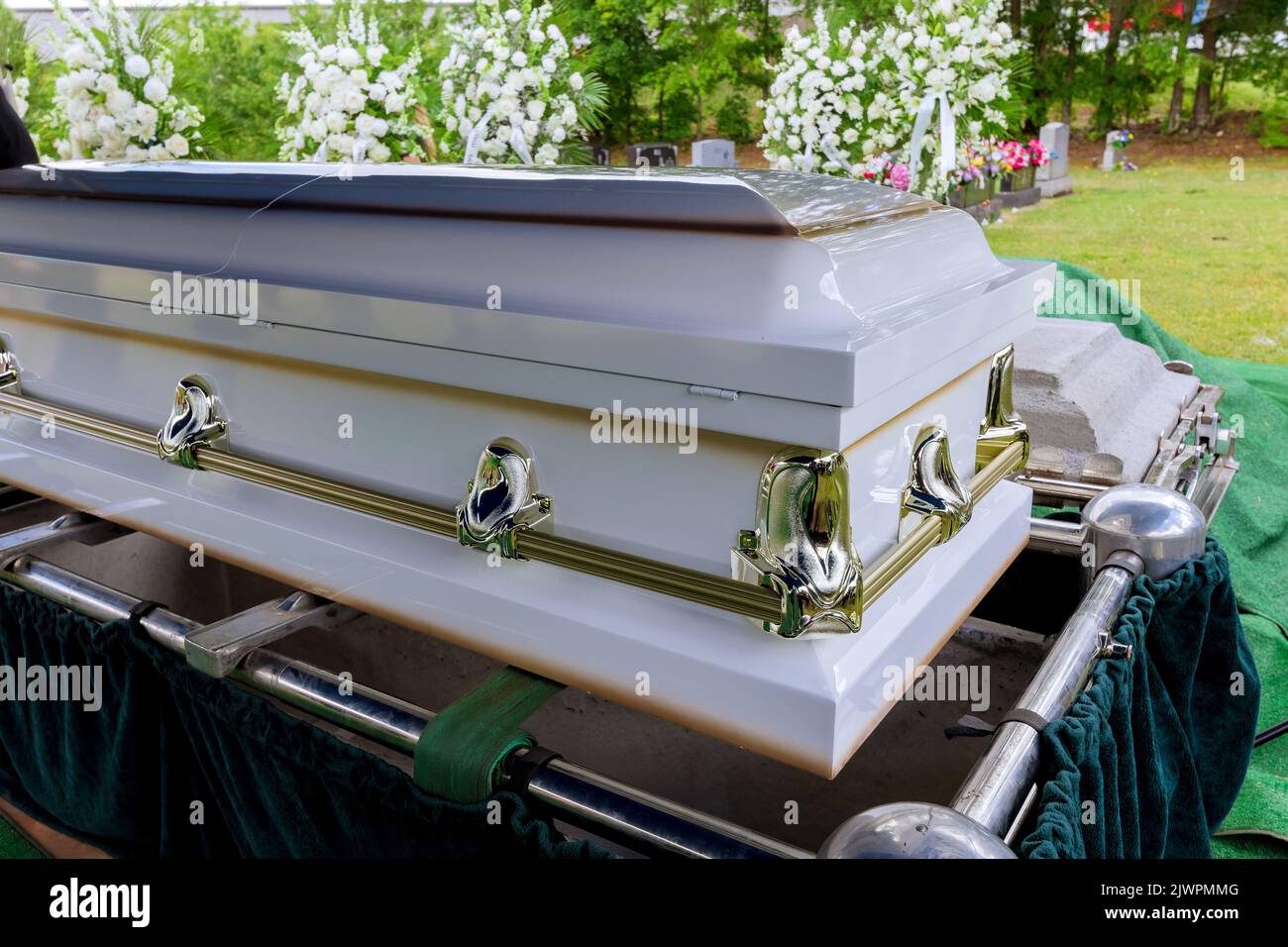 Trauerdienst auf dem Friedhof mit Sarg auf dem Aufzugssystem des automatischen Sinkens in das Grab Stockfoto