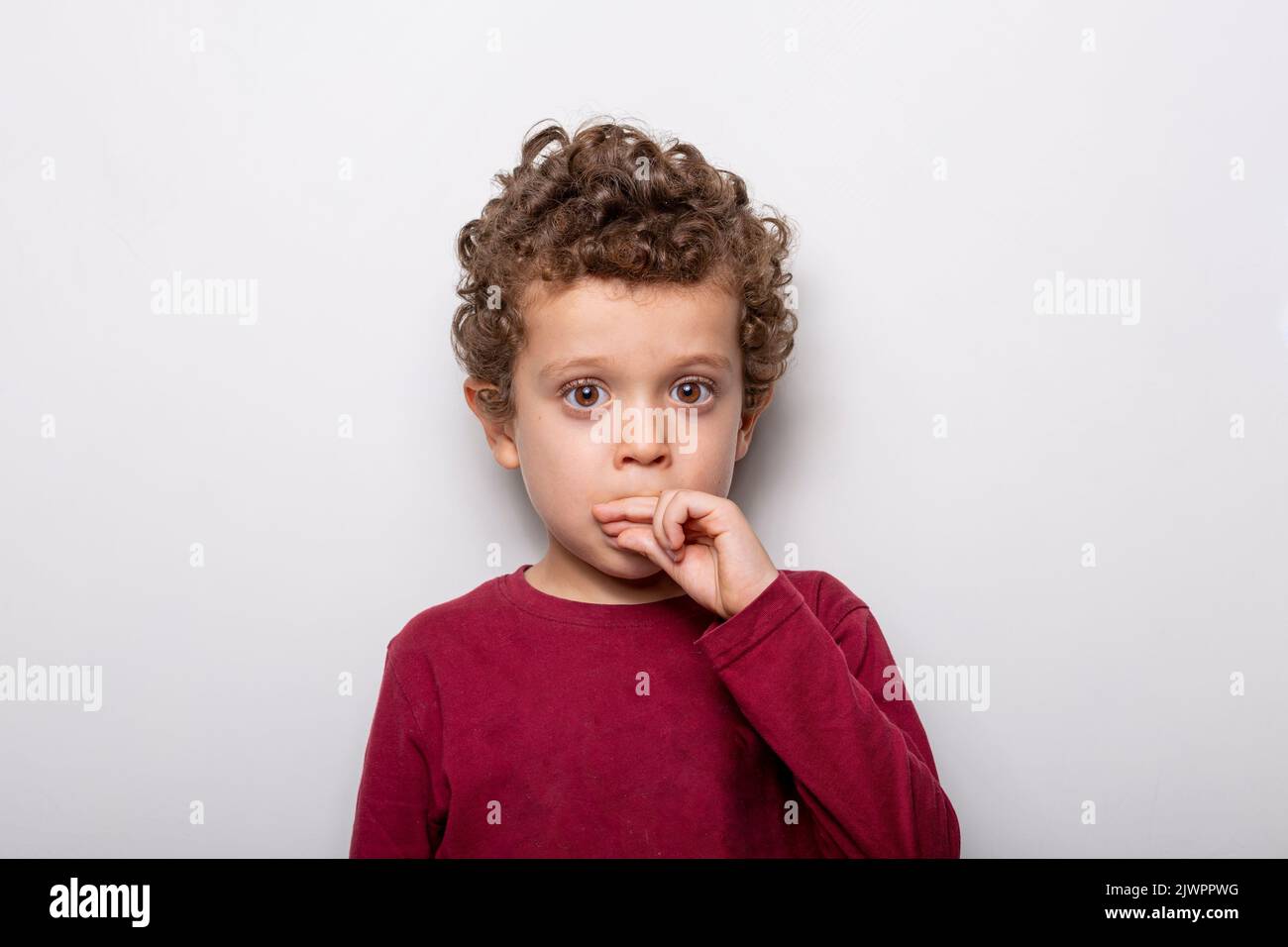 Niedlicher kleiner Junge mit braunen Augen und lockigen Haaren auf weißem Hintergrund Stockfoto