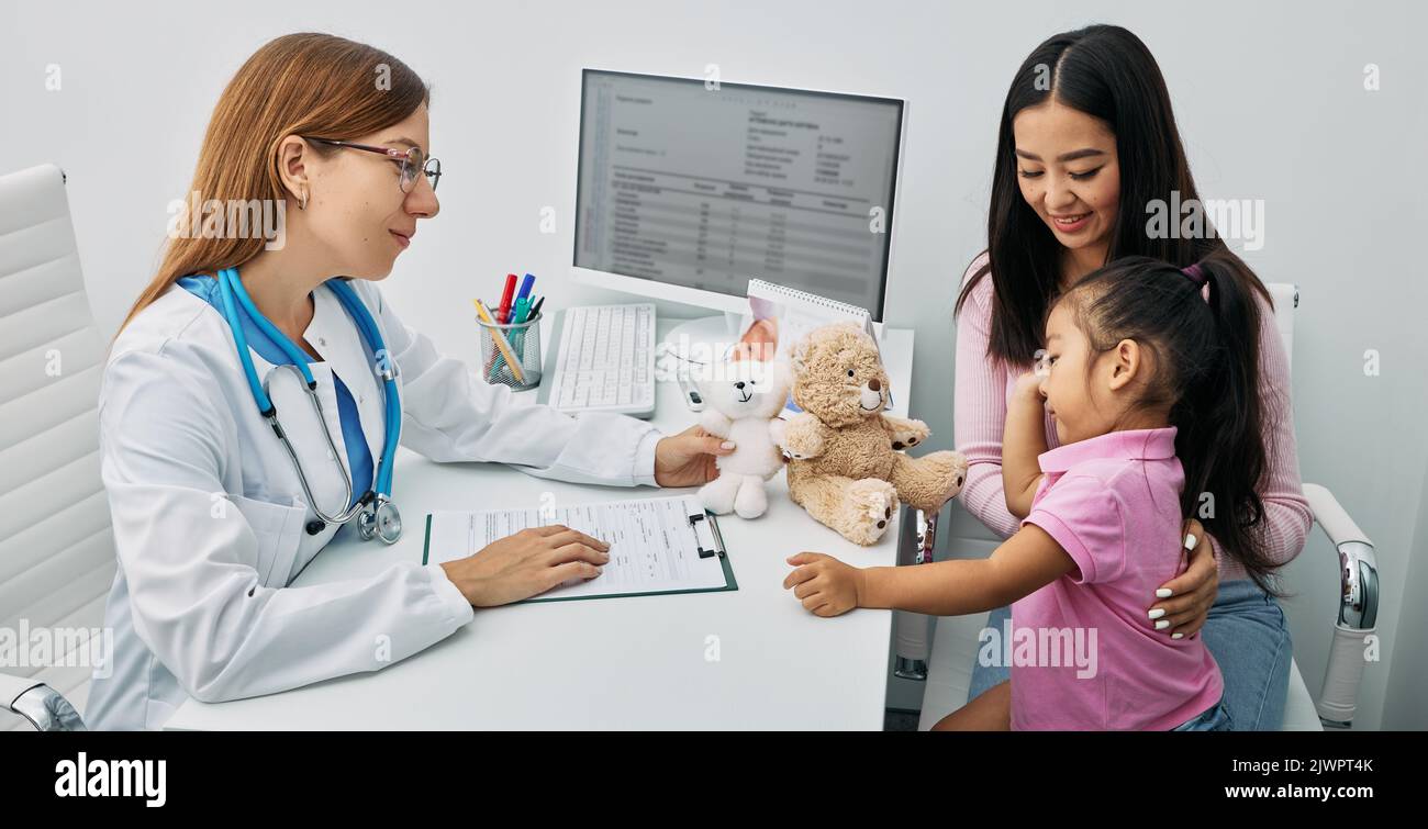 Asiatische kleine Mädchen mit ihrer Mutter während eines Besuchs bei Kinderarzt. Rücksprache mit dem Kinderarzt Stockfoto