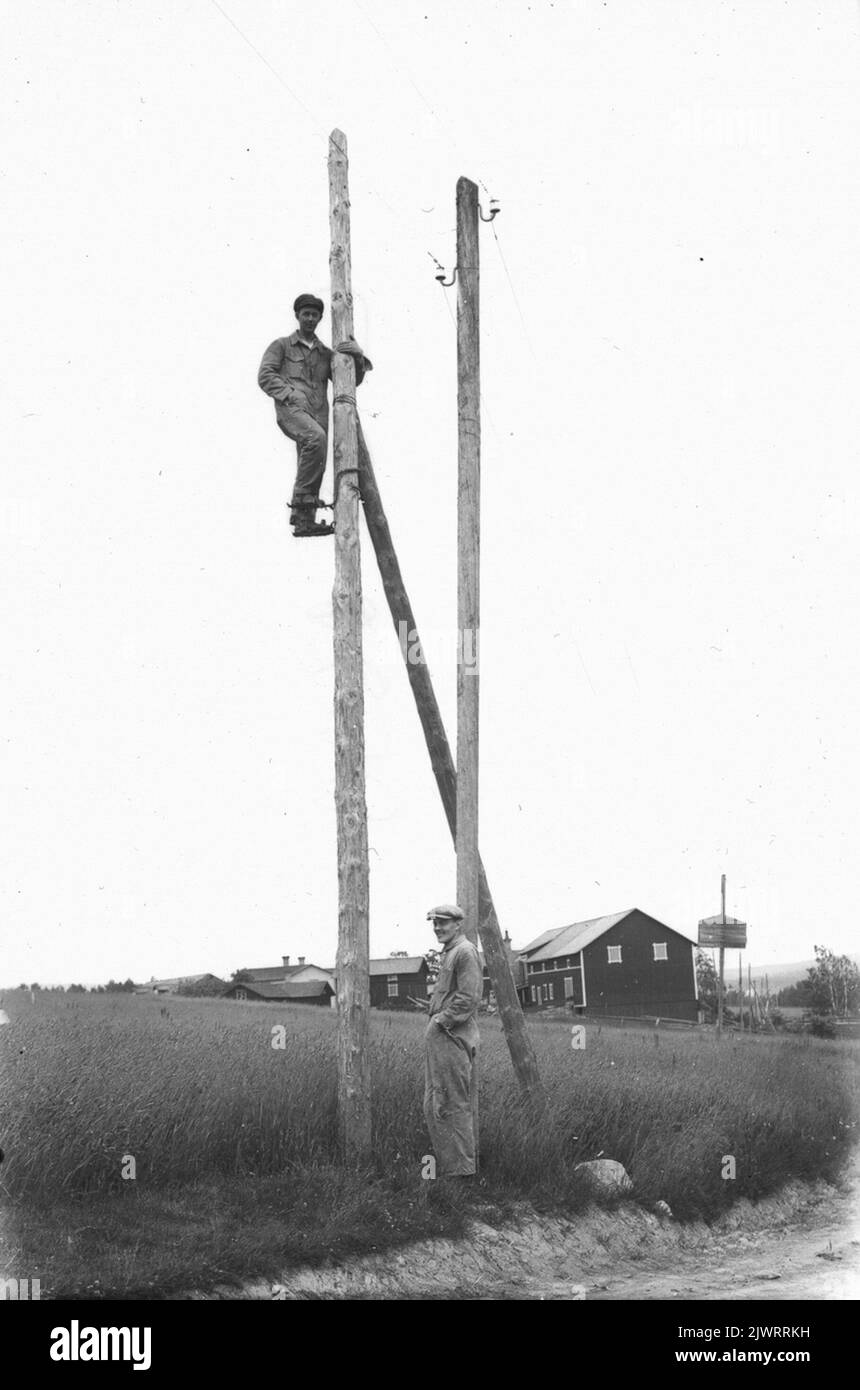 Zeichnung der Stromleitung neben Nils-Nils auf dem Weg hinunter zur Mühle. Auf der Post Mjölnar-Viktor (Olsson), der andere ist der Bruder Olle. Foto wahrscheinlich 1922. Dragning AV elledning intill Nils-Nils på vägen ner till kvarnen. på stolpen Mjölnar-Viktor (Olsson), den andre är brodern Olle. Foto förmodligen 1922. Stockfoto