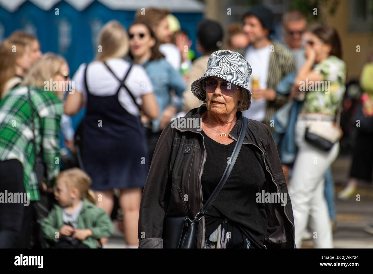 Ältere Frau mit Sommerhut auf der Kallio Block Party 2022 im Bezirk Alpila in Helsinki, Finnland Stockfoto