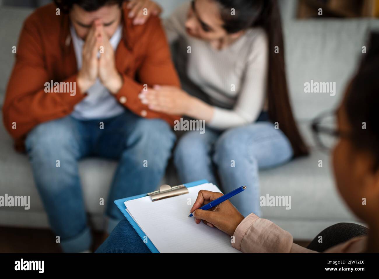 Behandlung von Depressionen. Unglückliche kaukasische Frau beruhigt den weinenden Mann nach Rücksprache mit dem Psychologen Stockfoto