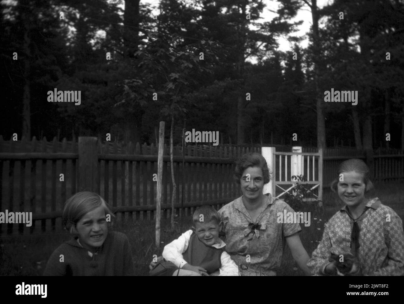 Hier sitzen die Kinder Brundin 1929 mit der Magd Gertrud. Sören sitzt in ihren Armen, Eva links und Ingrid rechts. Die Familie hatte eine Katze namens Snurran, die auf Ingrid's Knie sitzt. Här sitter barnen Brundin tillsammans med hembiträdet Gertrud 1929. Sören sitter i hennes famn, Eva till vänster och Ingrid till höger. Familjen hade en katt som hette Snurran, som sitter i Ingrids knas. Stockfoto