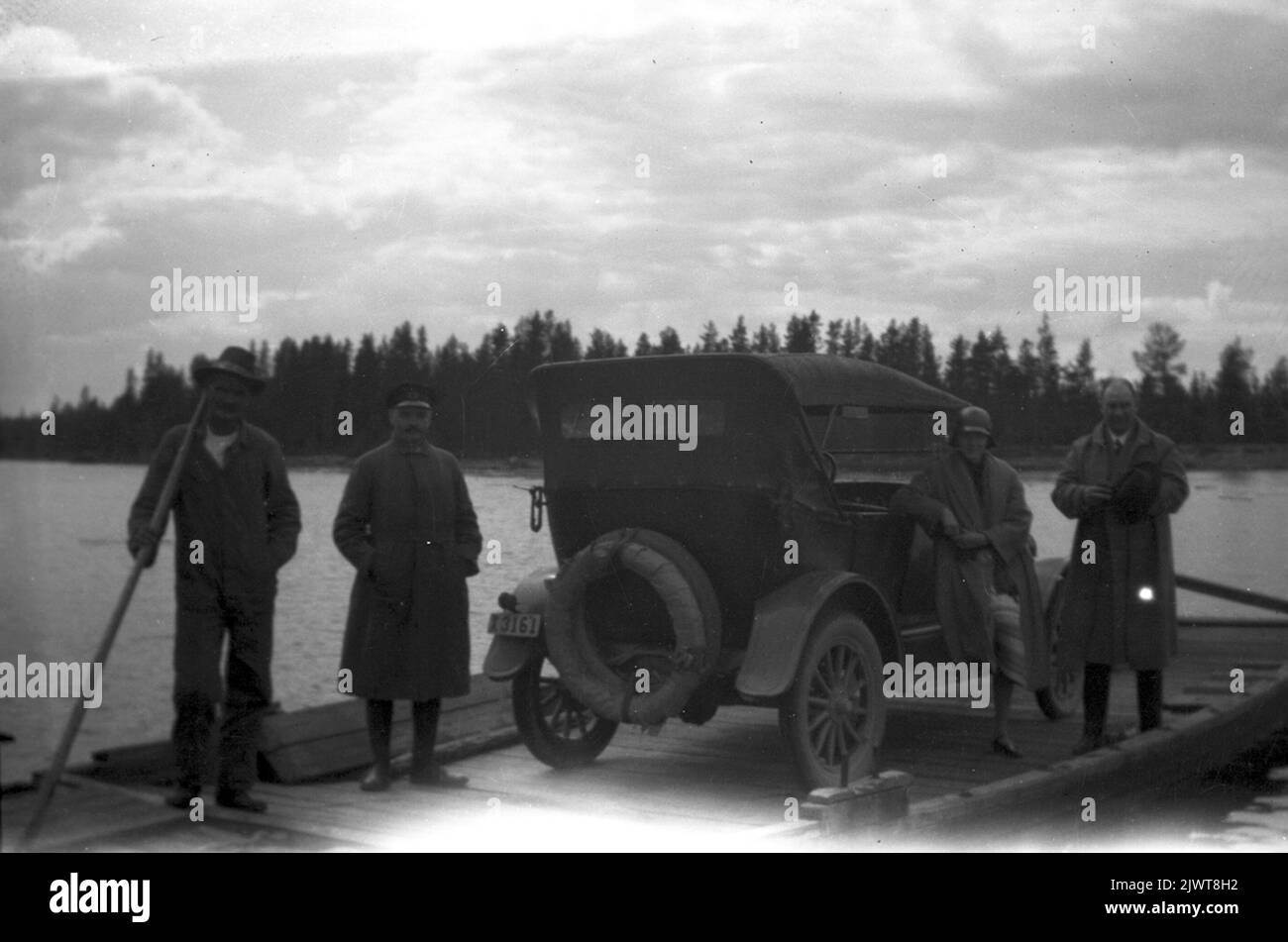 David Brundin begrüßt Elis Öhrn, der auf der Ferry Karlen auf der linken Seite steht, in einer Fahrermütze. Elna und David Brundin auf der rechten Seite. Das Auto eine Overland 1924 mit 4 Zylindern. David Brundin hälsar på Elis Öhrn, som står vid färjekarlen till vänster, i chaufförsmössa. Elna und David Brundin bis höger. Bilen en Overland 1924 med 4 cylinlar. Stockfoto