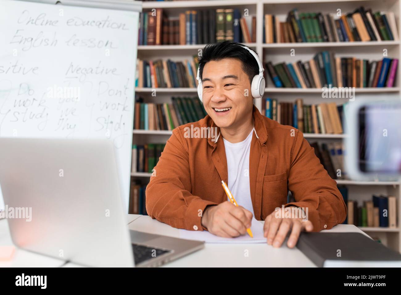 Chinesischer Lehrer Nimmt Notizen Lehre Online Über Laptop Am Arbeitsplatz Stockfoto