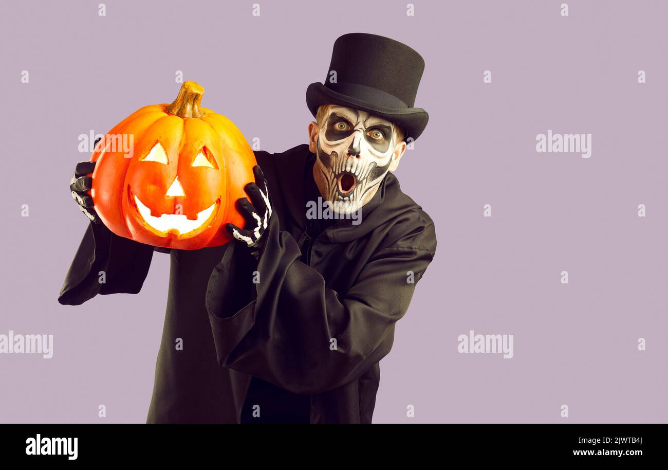 Lustig überrascht Mann im Skelett Halloween Kostüm halten Jack o Laterne und Blick auf die Kamera Stockfoto