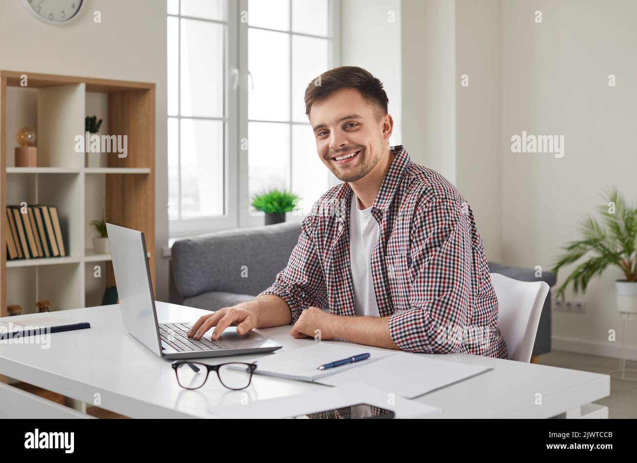 Erfolgreicher junger Geschäftsmann, der auf einem Laptop mit elektronischen Dokumenten im Büro sitzt. Stockfoto