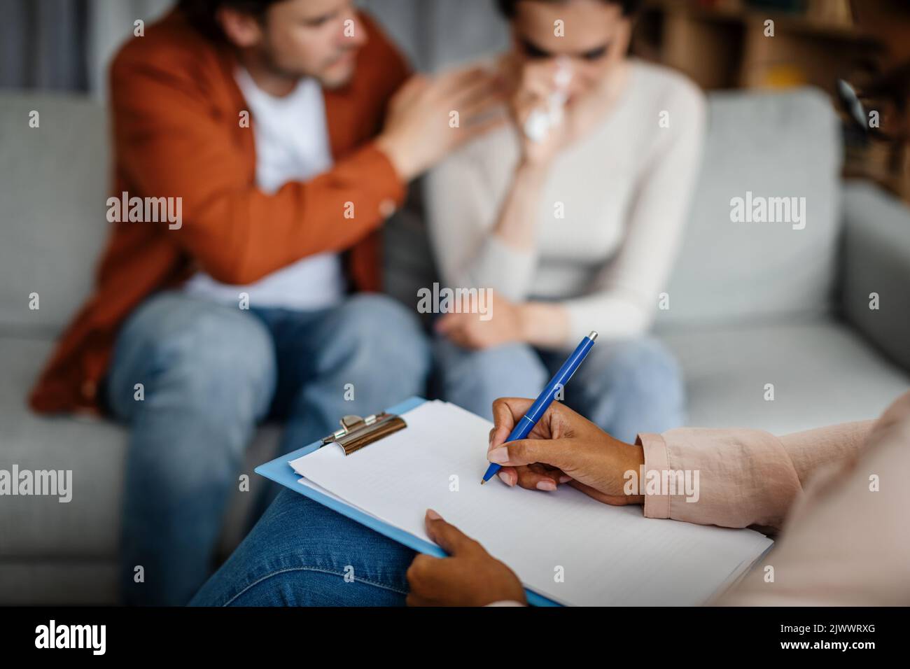 Trauriger junger europäischer Kerl beruhigt weinende Frau beim Treffen mit Psychologen im Inneren der Büroklinik, aus nächster Nähe Stockfoto
