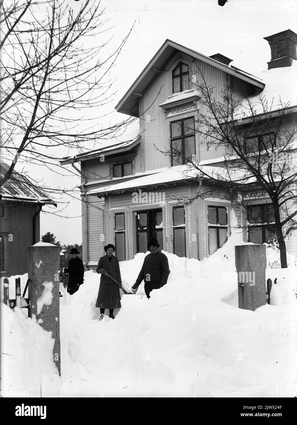 Jöns Wilander und Tochter Anna Sofia schießen Schnee vor dem Haus am Kvistholmsvägen in Norrsundet. Frau Sofia ist auf der linken Seite. Jöns Wilander och dottern Anna Sofia skottar skö framför huset på Kvistholmsvägen i Norrsundet. Hustrun Sofia står till vänster. Stockfoto