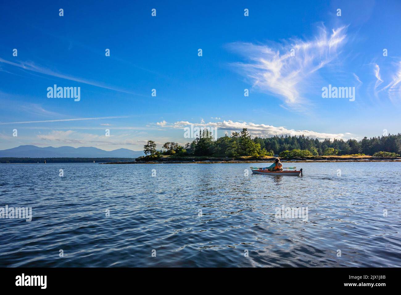 Eine einsame Paddler Kajakfahren in der malerischen und ruhigen Gewässer der Gulf Islands British Columbia an einem sonnigen Nachmittag. Stockfoto