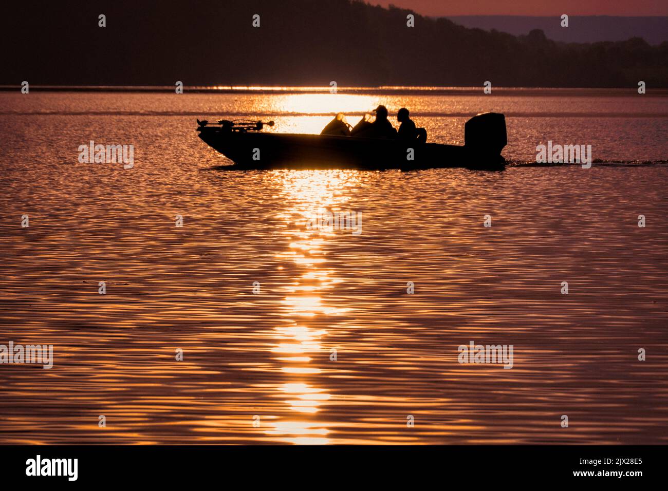 Bass Fischer in einem Bass Boot auf dem See, am frühen Morgen Sonnenaufgang. Stockfoto