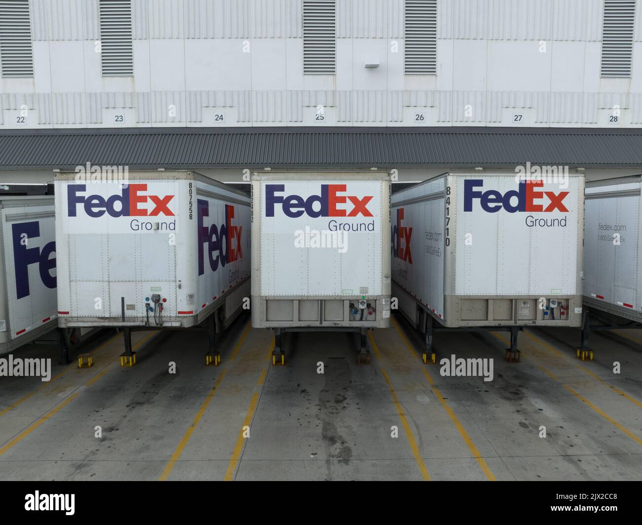 Eine Nahansicht der FedEx-Anhänger, die an einem Federal Express-Versandterminal angedockt sind; das FedEx-Logo ist auf jedem Anhänger zu sehen. Stockfoto