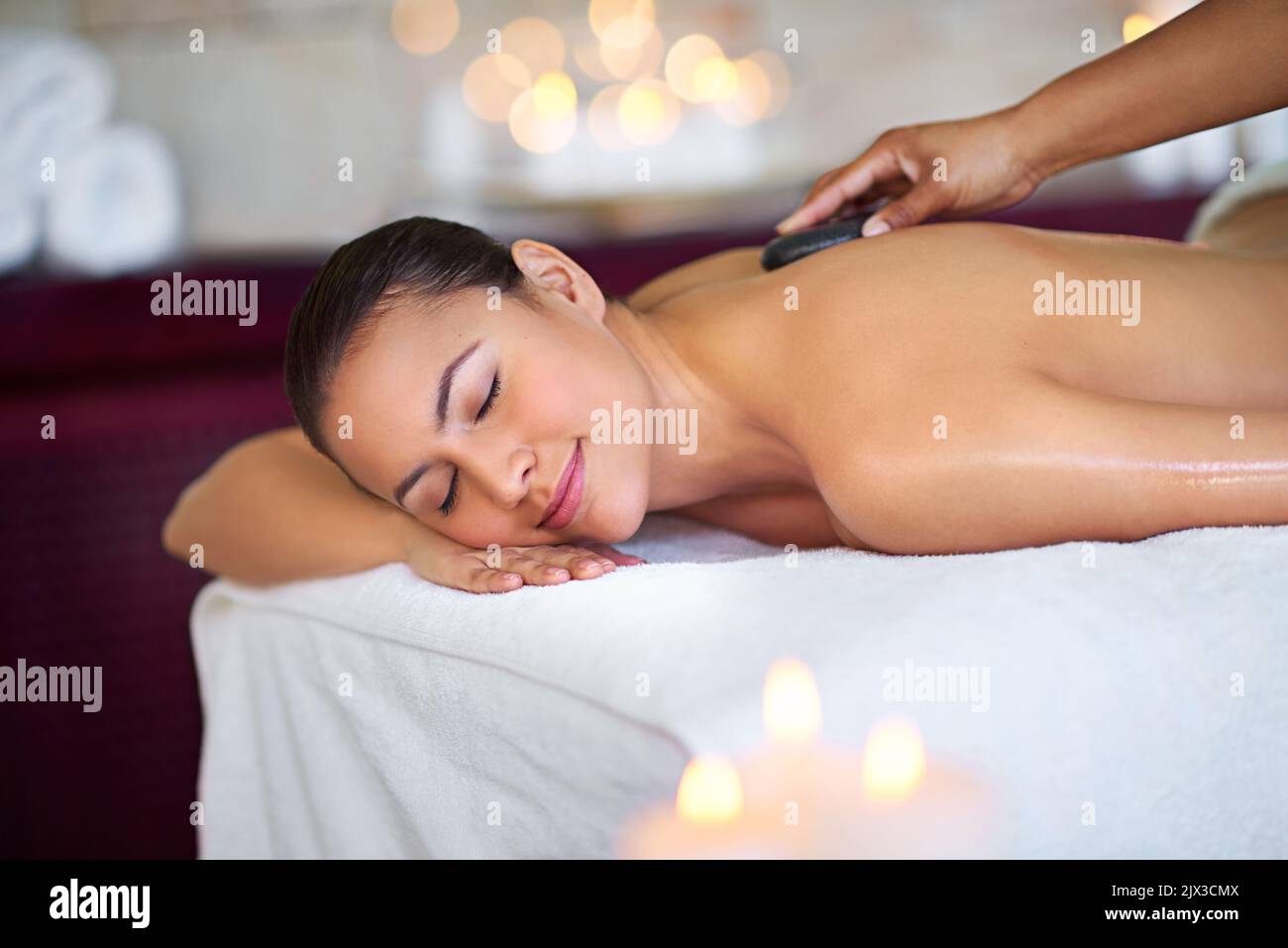 Wenn Sie sich öffnen und entspannen, können Sie Wunder finden. Eine junge Frau genießt eine Hot Stone Massage in einem Spa. Stockfoto