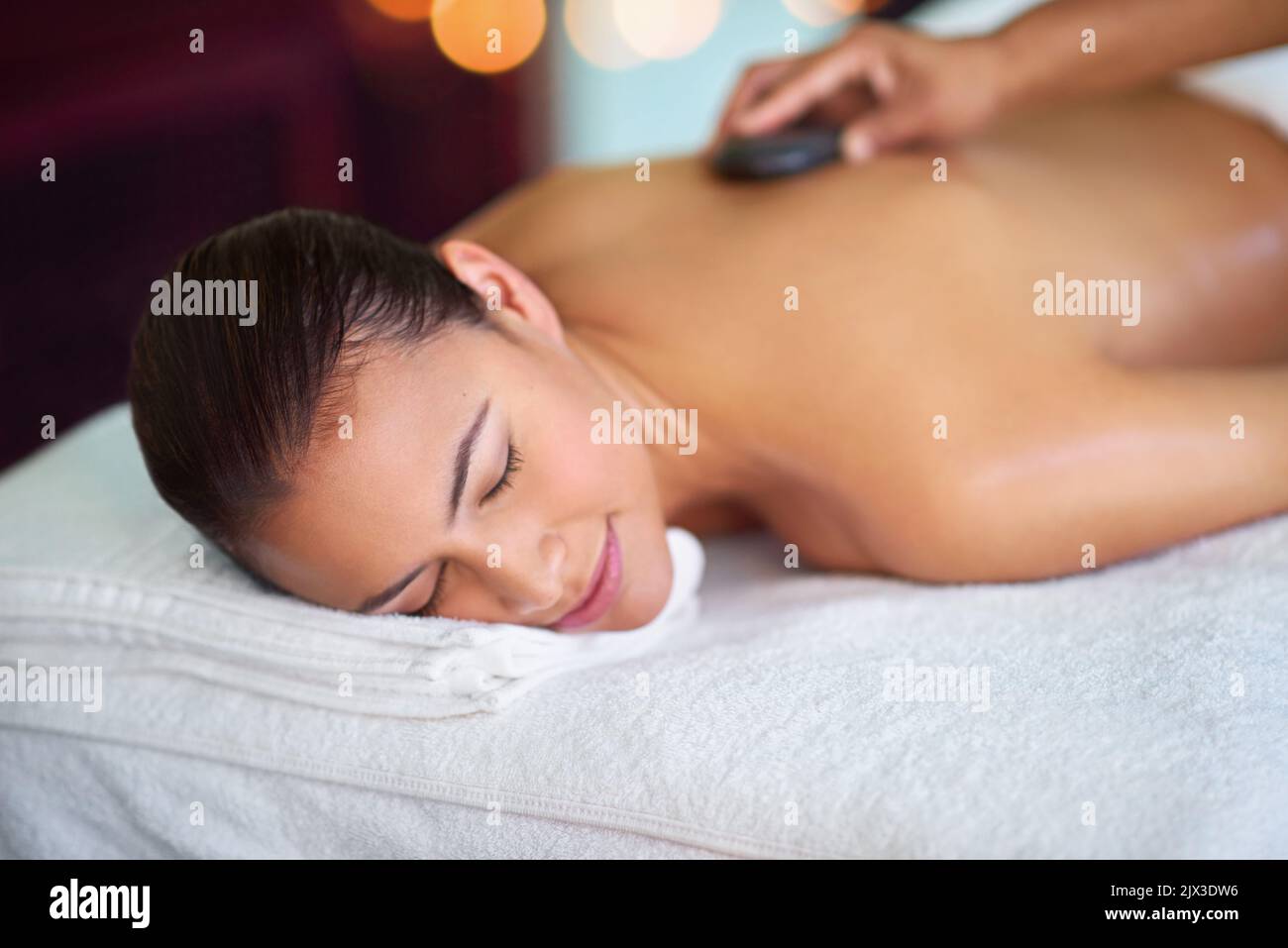 Nehmen Sie sich Zeit für Sei still., eine junge Frau, die eine Hot Stone Massage in einem Spa genießt. Stockfoto