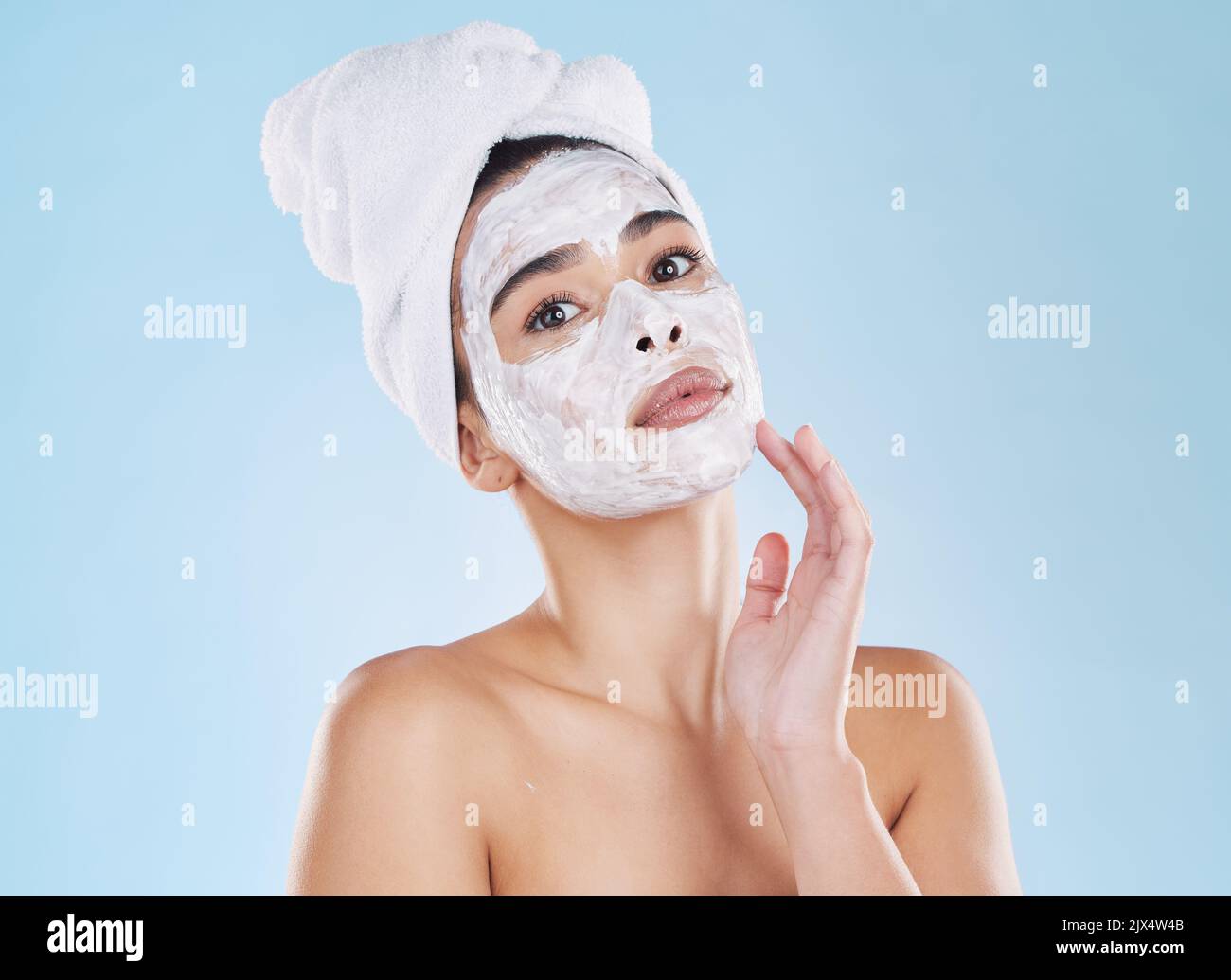 Hautpflege, Gesichtswäsche und Maske auf Frau im Studio mit blauem Hintergrund und Mockup. Junges Modell im Badetuch in einer Selbstpflege, Schönheit oder Kosmetik Stockfoto