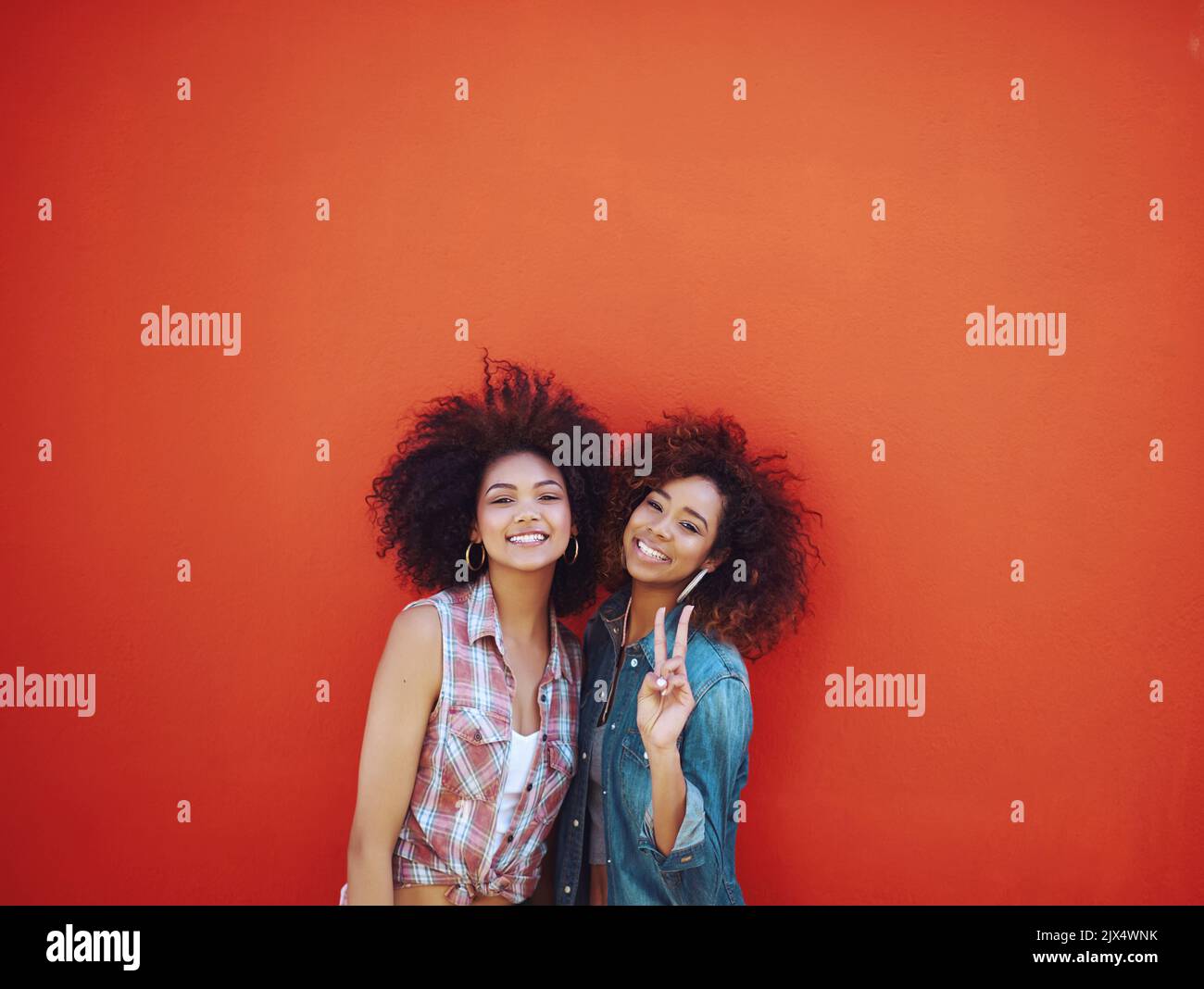 Bestieswaren wie zwei von einer Art. Zwei junge Freunde posieren vor einem roten Hintergrund. Stockfoto