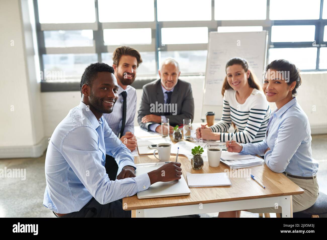 Eine Gruppe von Mitarbeitern, die um einen Tisch im Sitzungssaal sitzen. Stockfoto