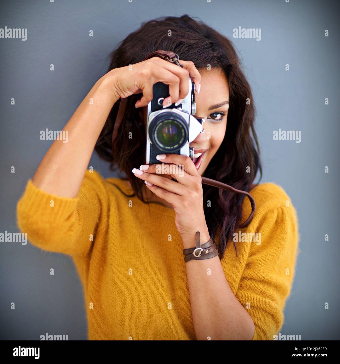 Ich möchte mich für immer an diesen Moment erinnern. Studioportrait einer jungen Frau mit einer Vintage-Kamera vor grauem Hintergrund. Stockfoto Ich möchte mich für immer an diesen Moment erinnern. Studioportrait einer jungen Frau mit einer Vintage-Kamera vor grauem Hintergrund. Stockfoto
