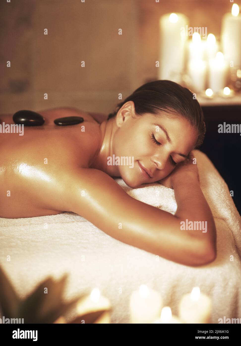 Ich verdiene es, mich verwöhnen zu lassen. Eine junge Frau genießt eine Massage mit heißen Steinen. Stockfoto
