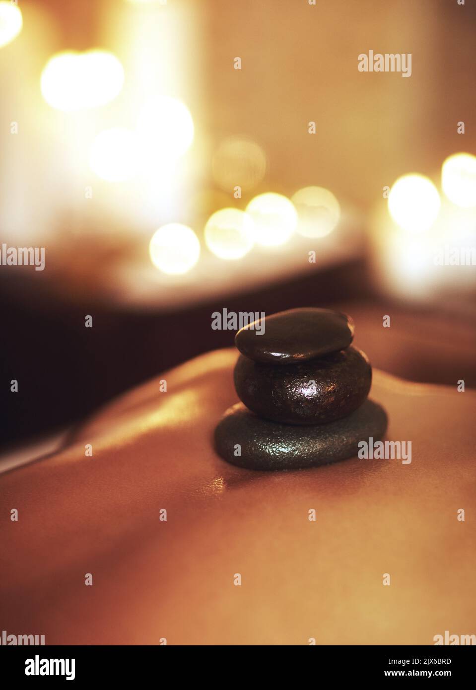 Eine junge Frau bekommt eine Hot Stone Massage. Stockfoto