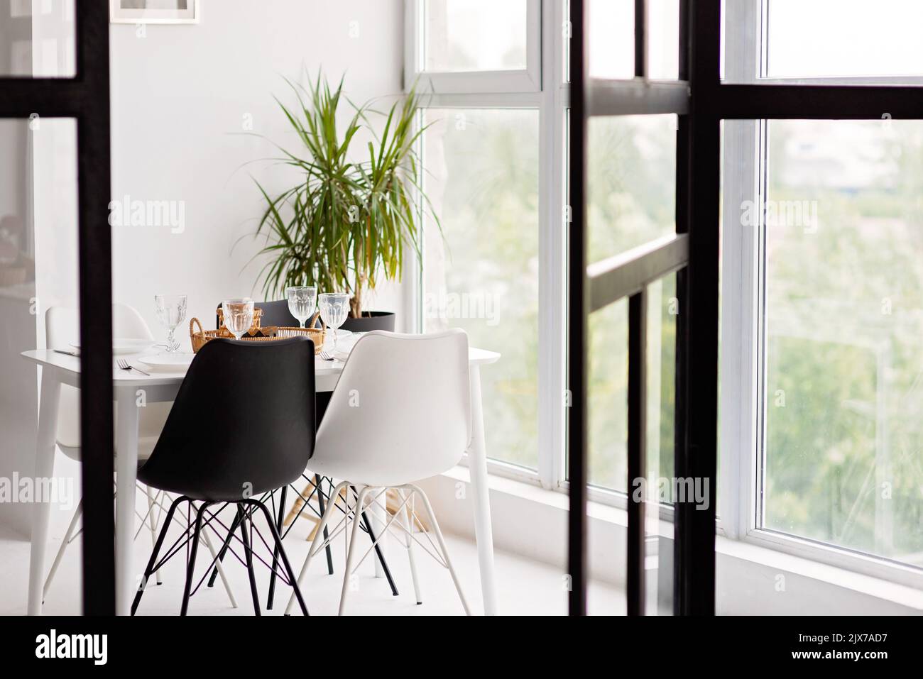 Modernes Interieur mit gemütlicher Küche, Esszimmer, weißen Möbeln, Stühlen, Schüsseln. Konzeptionelles Dekor-Design, Werbung, Hypothek für ein junges Fam Stockfoto
