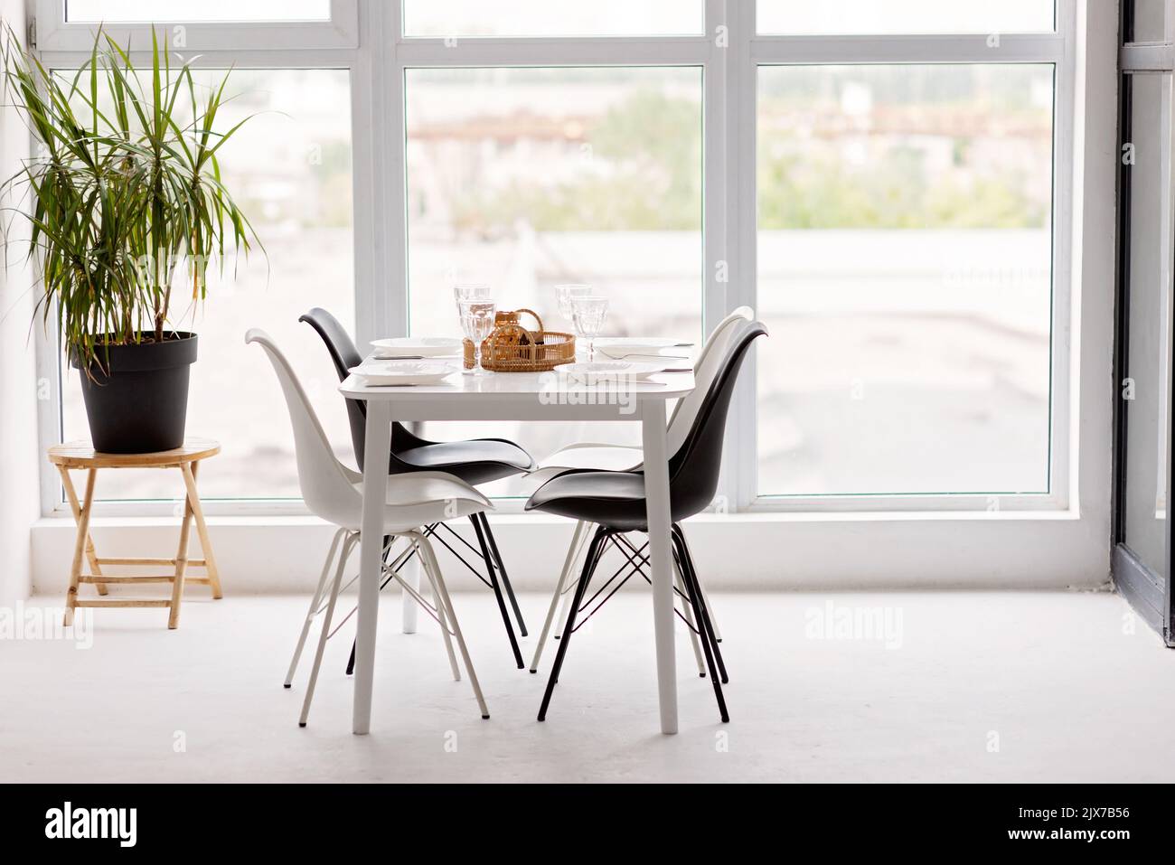 Modernes Interieur einer gemütlichen Küche im Esszimmer, weiße Möbel, vor dem Hintergrund eines Panoramafensters. Konzeptionelles Dekor, Haushypothek Stockfoto