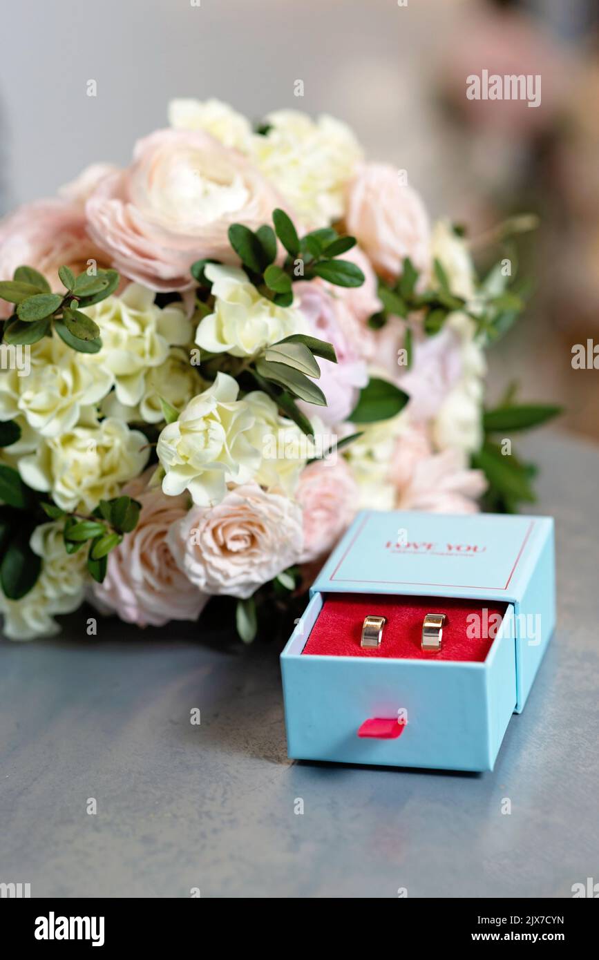 Ein Paar schöner Eheringe und ein zartes Brautstrauß aus Rosen. Hochzeitszeremonie. Weicher, selektiver Fokus. Stockfoto