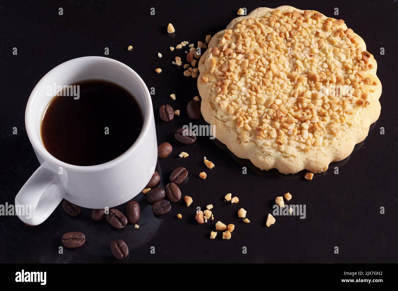 Tasse Kaffee und Lebkuchen mit Nüssen auf schwarzem Hintergrund Nahaufnahme Stockfoto