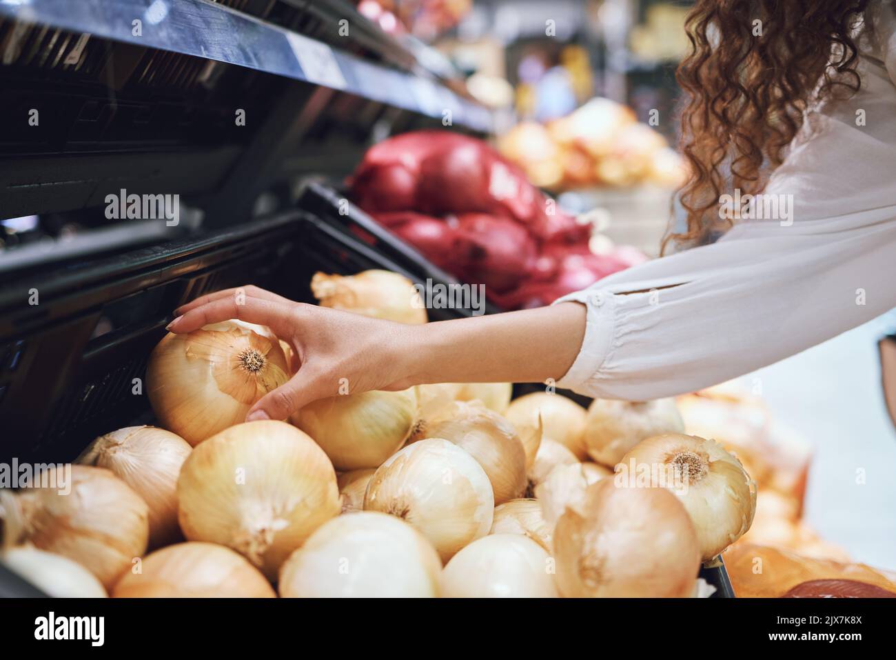 Gemüse, Lebensmitteleinkäufe und Gesundheit, während ein Kunde frische Zwiebeln im Supermarkt oder im Lebensmittelgeschäft wählt. Nahaufnahme der Hände einer Frau, die vegan kauft Stockfoto