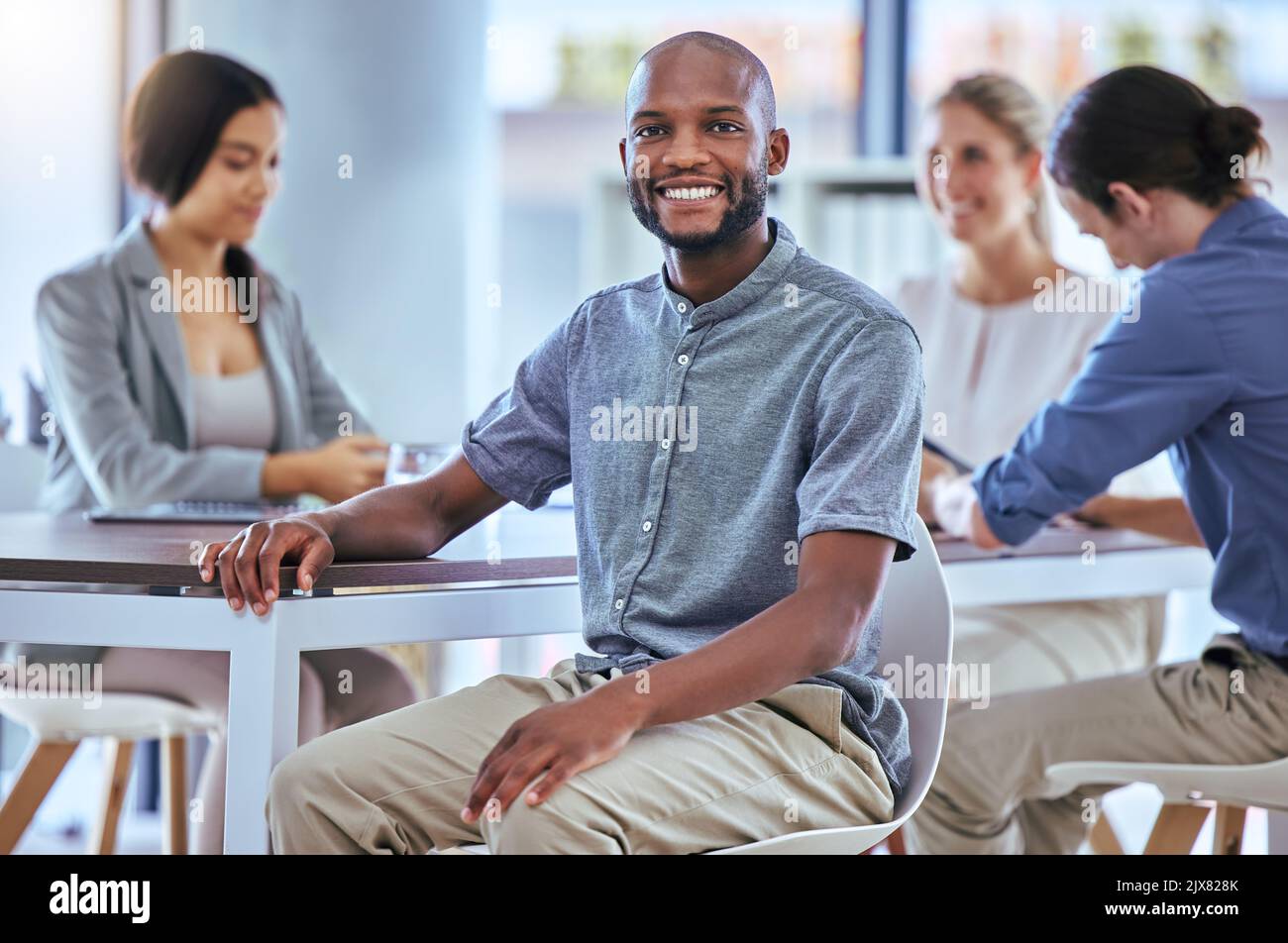 Porträt eines glücklichen Geschäftsmannes, der bei einer Teamplanungsbesprechung bei der Arbeit lächelt. Ein stolzer Mitarbeiter in einem Büro mit der Gruppe, während er über neue Innovationen spricht Stockfoto