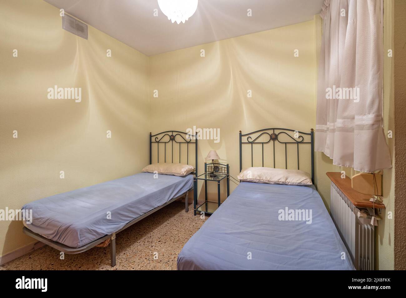 Zwei Betten in einem kleinen, einfachen Schlafzimmer in einem Hostel, Motel oder Gästehaus. Konzept der günstigen Unterkunft für Miete oder Reise Stockfoto