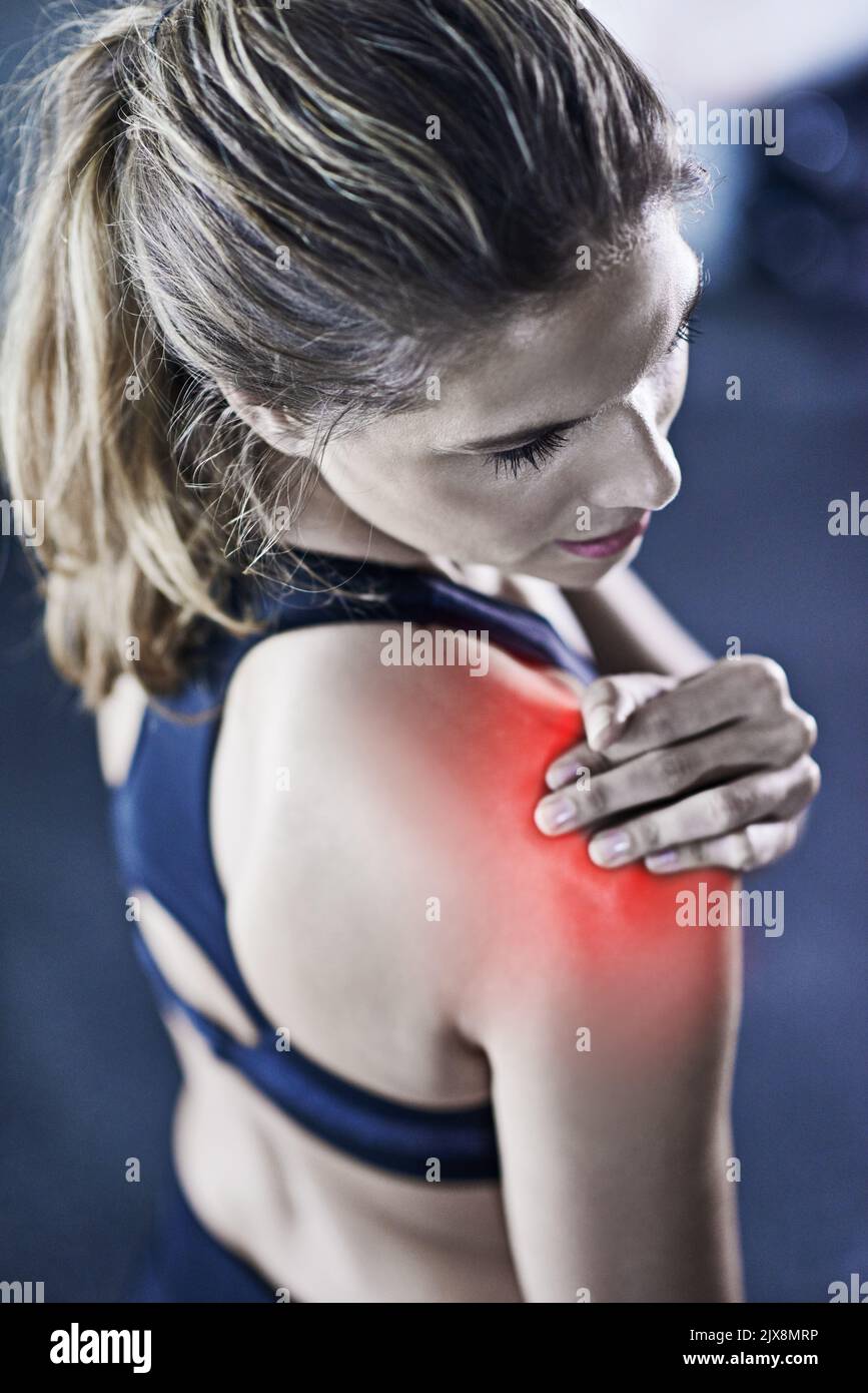 Muskelkater ist schmerzhaft, aber es lohnt sich. Eine junge Frau hält ihre verletzte Schulter, die rot hervorgehoben ist. Stockfoto