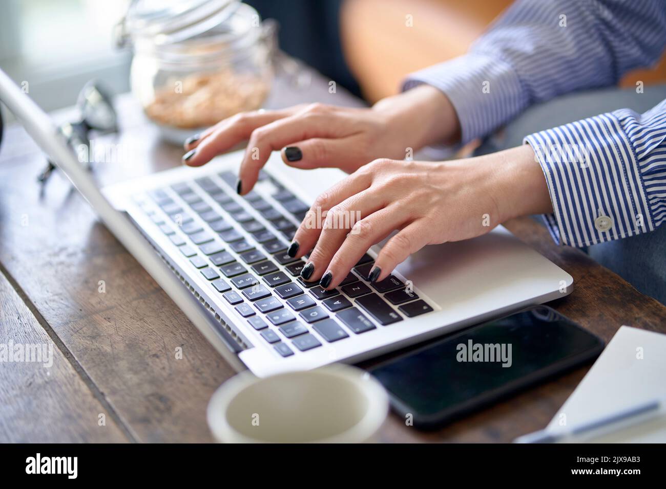 Nahaufnahme von Händen und Fingern einer asiatischen Frau, die von zu Hause aus mit einem Laptop arbeitet Stockfoto